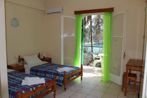 a room with two beds and a window with green curtains at Belvedere Paleo in Paleokastritsa