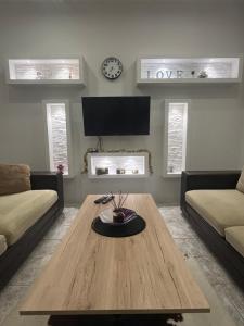 un soggiorno con tavolo, divano e TV di Cute and Cozy a Pale Altre 3 foto