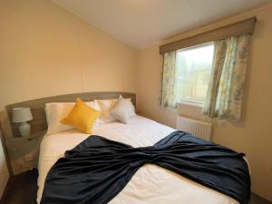 a bed with a black blanket on it with a window at Pass the Keys Cosy Welcoming 3BR in Beautiful Country Park in Beattock