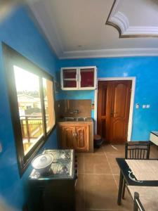 eine Küche mit blauen Wänden, einem Tisch und einem Fenster in der Unterkunft Chez Matis in Pointe-Noire