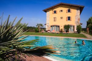 two people swimming in a swimming pool in front of a house at La Molinalda in Castelnuovo del Garda