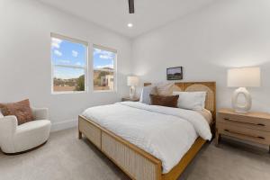 a white bedroom with a bed and a chair at Villa #33 at Bloomington Country Club condo in St. George