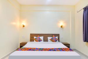 a bedroom with a large white bed with colorful pillows at Fabhotel Baga Tulip - 500M From Baga Beach in Baga