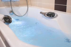 a bath tub filled with blue water with a faucet at Brit Hotel Dieppe in Dieppe