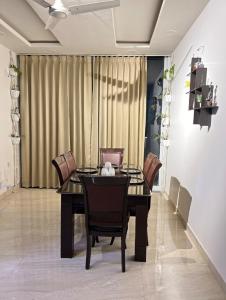 mesa de comedor con sillas y cortina en The Cozy Corner by DreamStays, en Jaipur