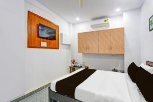 a bedroom with a white bed and a wooden cabinet at Super Hotel O Karmanghat Near TKR khaman in Hyderabad