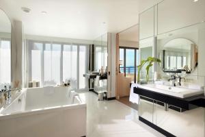 a bathroom with a tub and two sinks and a mirror at Hyatt Regency Nice Palais de la Méditerranée in Nice