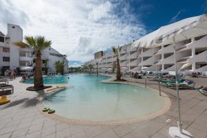 a swimming pool in a resort with palm trees and buildings at Paloma Beach Apartments in Los Cristianos