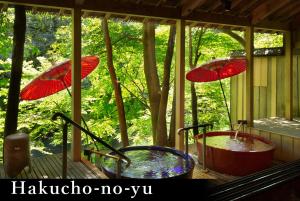 two hot tubs on a porch with umbrellas at Yamanaka Onsen Kagari Kisshotei in Kaga