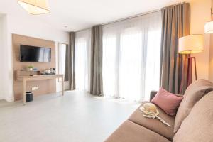 a living room with a couch and a large window at Comfort Aparthotel Cannes Mandelieu in Mandelieu-la-Napoule