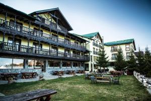 a large building with tables and benches in a yard at Complex Padina Ursului Fundata in Fundata