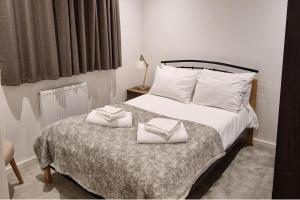ウェンズベリーにあるSunset View-Luxury 2-Bed House Near Birminghamのベッドとタオル2枚のある寝室