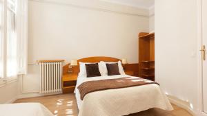 バルセロナにあるオスタル オリヴァの白いベッドルーム(ベッド1台、ラジエーター付)