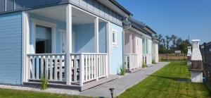 a row of houses with a porch at Domki letniskowe Pastelowe Ustronie in Ustronie Morskie