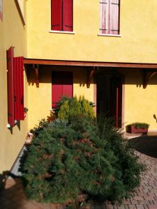 a yellow building with red windows and a large bush at Holiday Home La Moranda in San Fior di Sopra