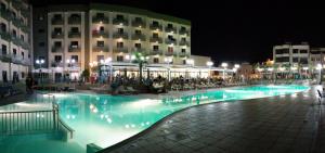 a swimming pool in front of a building at night at Topaz Hotel in St Paul's Bay