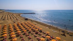 una spiaggia con molti ombrelloni e persone sulla spiaggia di Hotel Ca' Di Valle a Cavallino-Treporti