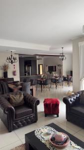 a living room with leather couches and a dining room at Cora's Boutique Bed & Breakfast in Swakopmund