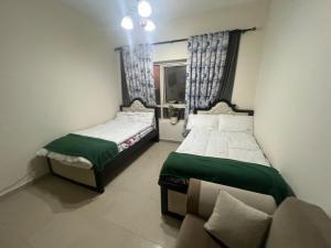 Duas camas num quarto com um sofá e uma janela em Smile Apartment Sharjah -FAMILY ONLY em Sharjah