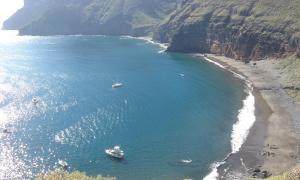 two boats in a body of water next to a beach at Albergue Montes de Anaga in El Bailadero