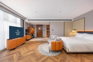 青岛Golden Tulip Qingdao Hongdao Exhibition Center Hotel的一间配有床和平板电视的酒店房间