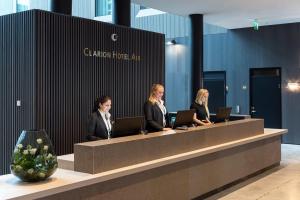 three women sitting at a reception desk with laptops at Clarion Hotel Air in Sola