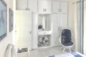 a white room with a chair and white cabinets at Charming Apartment, Pereybere, Terrace in Pereybere