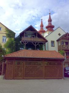 duży budynek z drewnianym garażem przed kościołem w obiekcie Apartments U Kašny w mieście Kadaň
