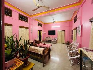 SibsāgarParag Abode - A Luxury Homestay的客厅设有粉红色的墙壁和电视