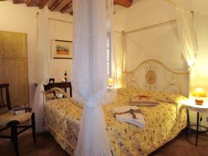 アシャーノにあるB&B Le Logge Di Sopraのベッドルーム(天蓋付き白いベッド1台付)