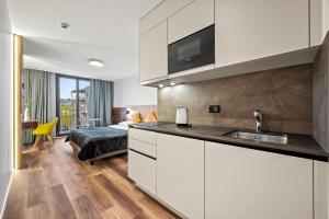 a kitchen with white cabinets and a bed in a room at Hine Adon Fribourg Nord in Fribourg