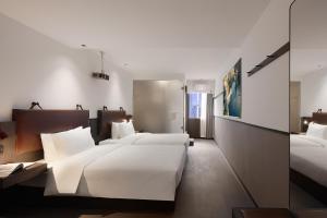 a hotel room with two beds and a mirror at Mcsrh Hotel-Guiyang Xiaoshizi in Guiyang