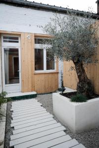 una casa con un albero davanti di La Tête Penchée - Maison Duplex 2 Chambres et Jacuzzi a Deûlemont