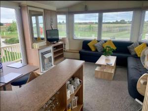 a living room with a blue couch and a fireplace at 8 Berth 3 bed caravan Golden palm ML9 in Chapel Saint Leonards
