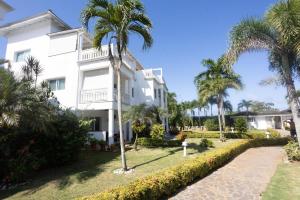 a white building with palm trees in front of it at Las Terrenas, La Fenice, Playa Popy in Las Terrenas