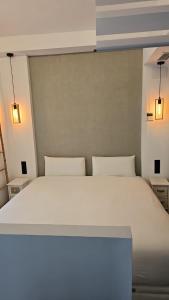 1 cama blanca grande en una habitación con 2 luces en Suite Foro Romano 2 huespedes, en Córdoba 5 fotos más