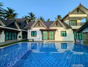 a villa with a swimming pool in front of a house at Flouzan Villa in Setiu