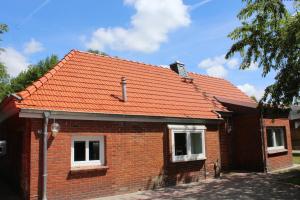 ostfriesisches Ferienhaus Anno 1899 في Großheide: منزل من الطوب الاحمر بسقف برتقالي