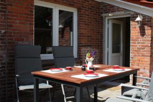 ostfriesisches Ferienhaus Anno 1899 في Großheide: طاولة وكراسي خشبية على الفناء