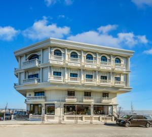 a white building with balconies and a car parked in front at Nenessa Airport Hotel in Arnavutköy