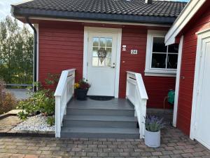 a red house with stairs leading to a white door at Konglefaret - apartment in Hønefoss in Hønefoss