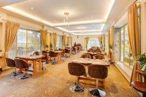 a restaurant with tables and chairs and windows at La Nicholas Lake View by Summit Hotels in Mawlyngkhung