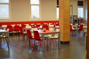 a dining room with tables and red chairs at The Factory Residence Hall in Segovia