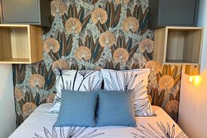 a bed with two pillows in a bedroom with a wallpaper at Le Cottage Détente in Biscarrosse