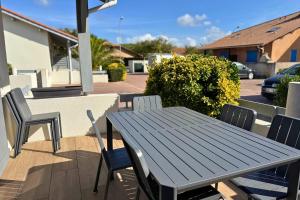 a wooden picnic table and chairs on a patio at Le Cottage Détente in Biscarrosse