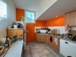 a kitchen with orange walls and wooden cabinets at Maison à l'orée du bois in Frangy
