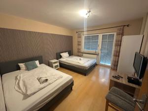 a small room with two beds and a television at Apartment with top kitchen and 3 sleeping rooms in Untermeitingen