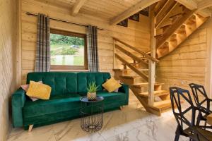 a green couch in a room with a wooden wall at Domki GliczarowSKI z Jacuzzi & Sauna in Zakopane
