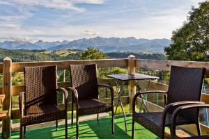 two chairs and a table on a balcony with mountains at Domki GliczarowSKI z Jacuzzi & Sauna in Zakopane