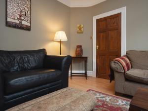 a living room with a black leather couch and a chair at Pass the Keys Spacious and Comfortable 3 Bed Home in Birkenhead in Birkenhead